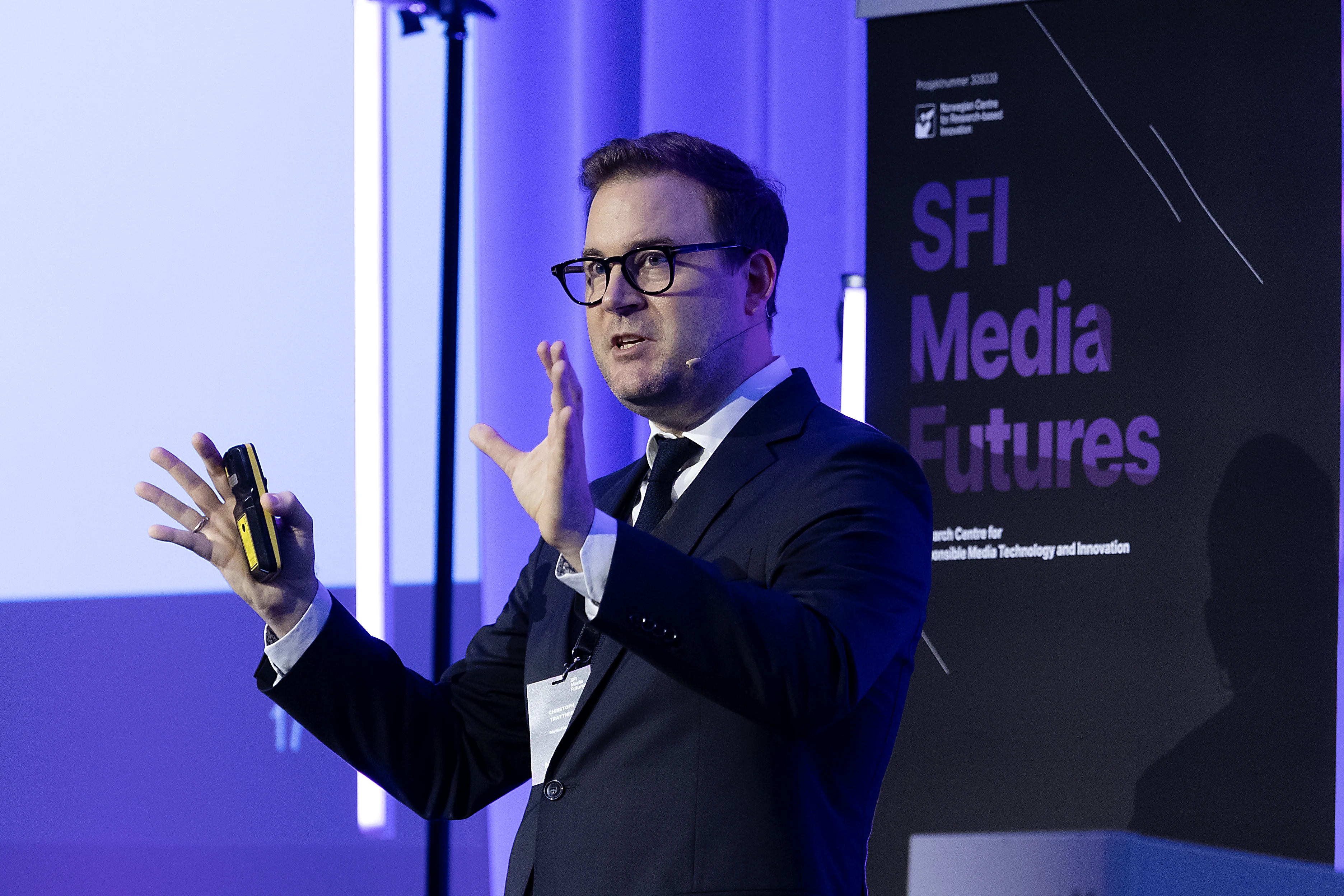 Christoph Trattner presenting on stage at the SFI MediaFutures Annual Meeting, gesturing while speaking.